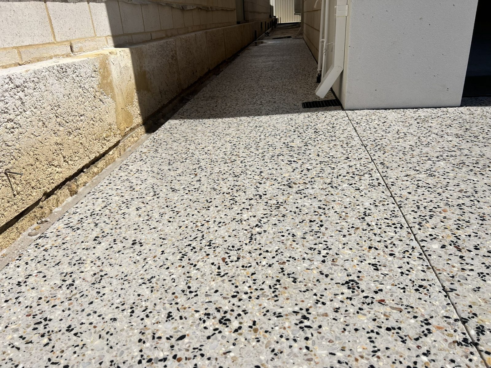 Exposed aggregate path beside a block wall
